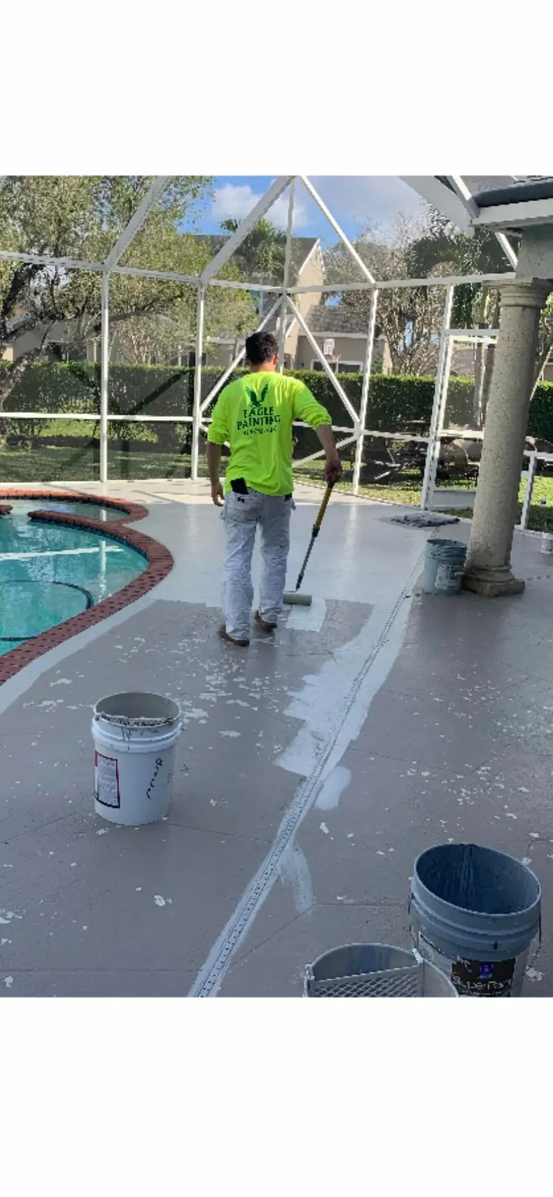 Eagle Painting technician pressure cleaning a pool deck at a Broward home