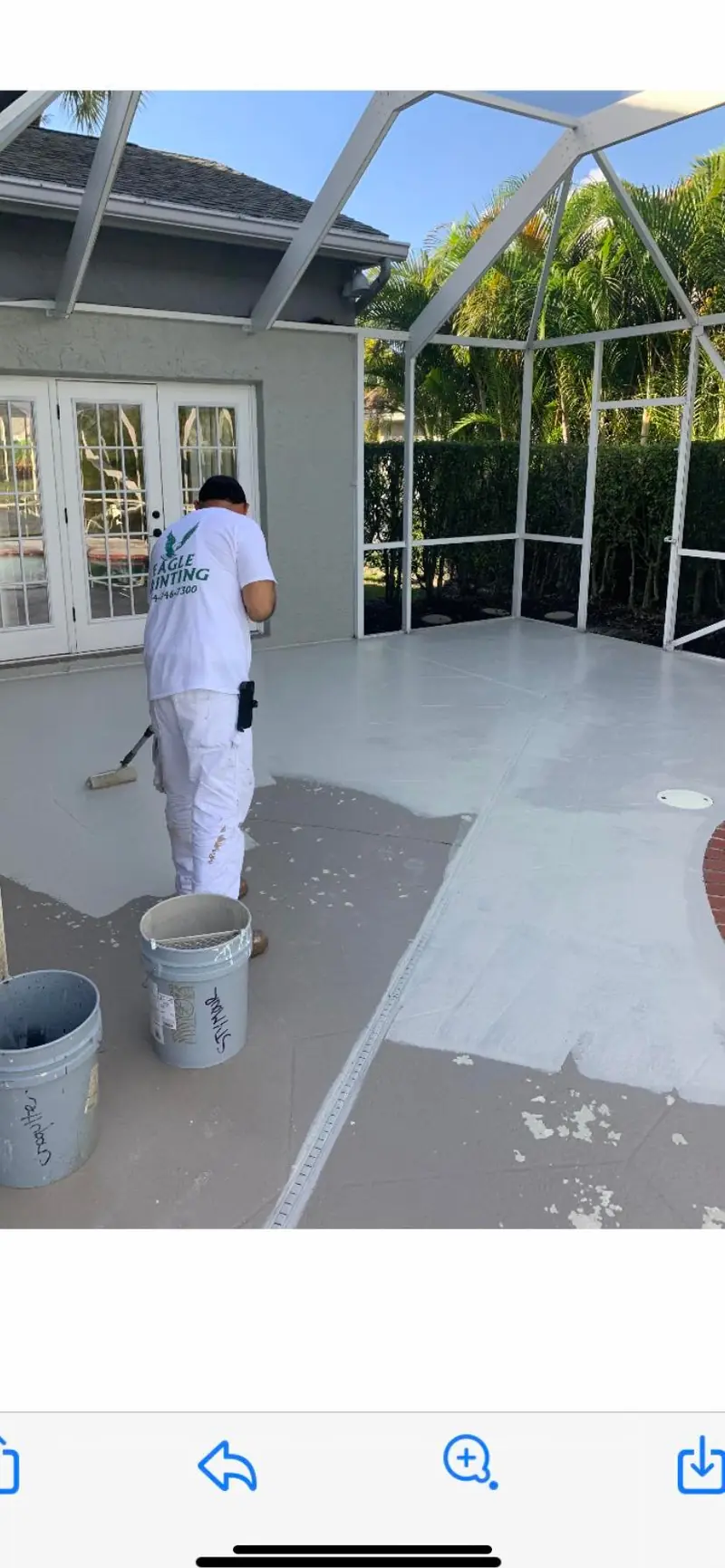 Eagle painter working on a lanai deck inside a pool screen enclosure