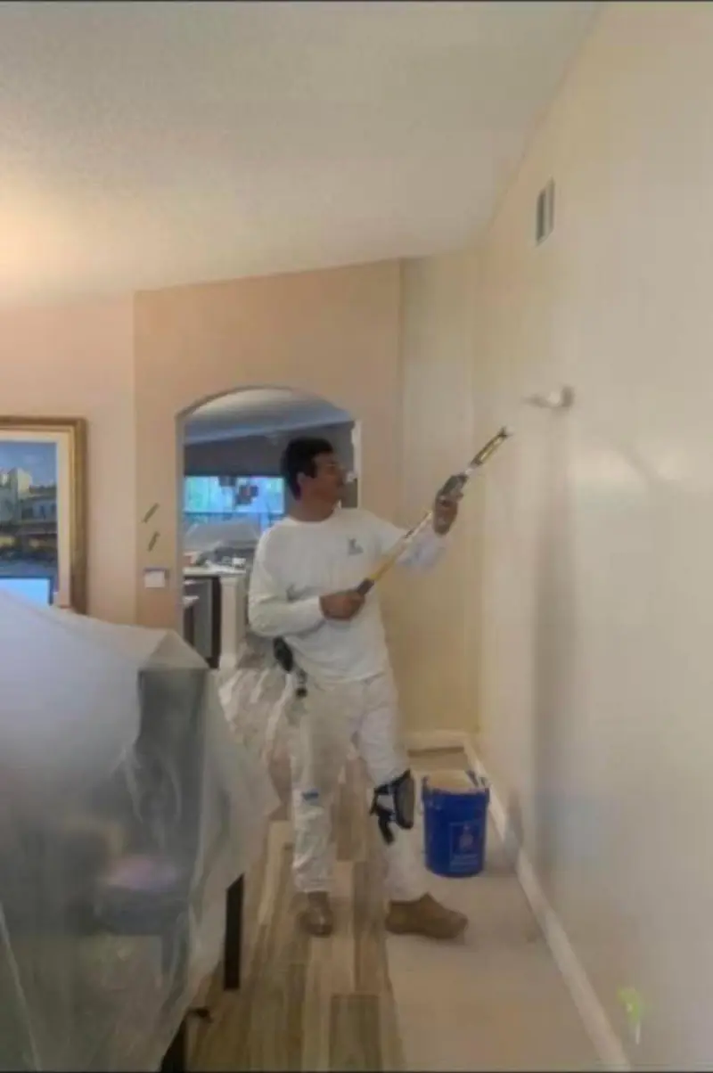 Painter rolling a fresh coat on a bedroom wall in a Broward County home