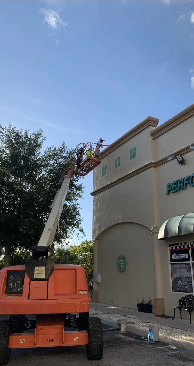 Eagle Painting crew working from an orange boom lift on a commercial plaza facade