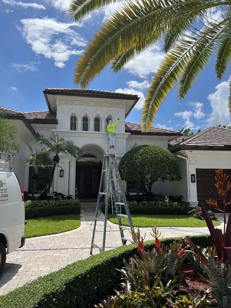 Mediterranean style home in Broward County with an Eagle painter on a ladder at the entry