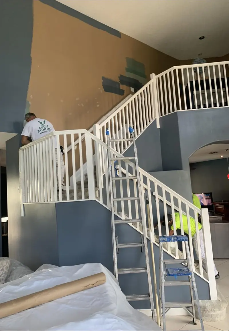 Eagle painter finishing a staircase railing inside a Broward County home