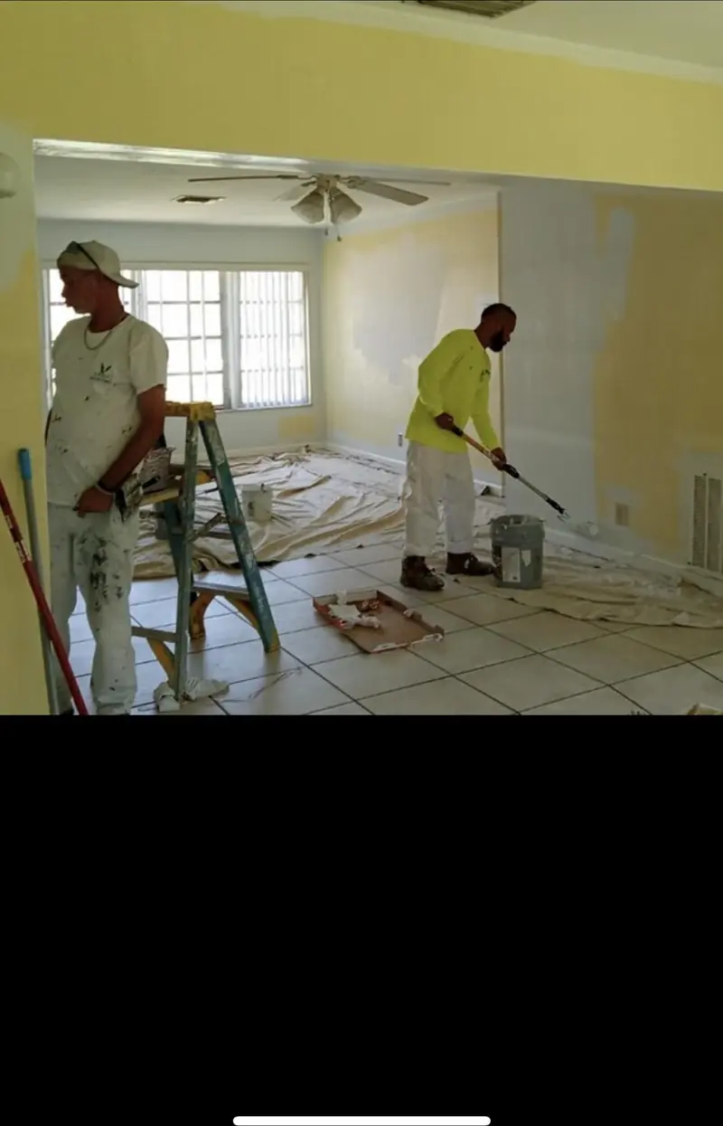 Two Eagle painters working in a living room with fresh yellow walls